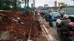 Pengendara melintas di dekat pekerja yang sedang mengerjakan proyek underpass di Jalan RA Kartini, Metro Pondok, Lebak Bulus, Jakarta, Rabu (22/3). Pembangunan underpass ini untuk mengurai kemacetan di perempatan Lebak Bulus. (Liputan6.com/Gempur M Surya)
