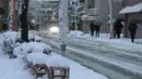 Warga melewati jalanan yang tertutup salju untuk menuju stasiun kereta bawah tanah di Tokyo,  Jepang, Senin (18/1). Akibat banyaknya tumpukan salju yang menyelimuti daerah metropolitan Tokyo, moda transportasi massa pun lumpuh. (AFP PHOTO/KAZUHIRO NOGI)