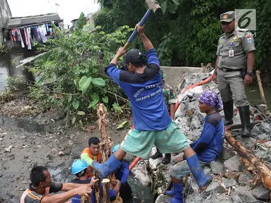 Petugas gabungan bergotong royong memperbaiki tanggul yang jebol di Kelurahan Jatipadang, Jakarta Selatan, Selasa (12/12). Perbaikan tanggul sementara itu dilakukan dengan membuat tanggul pasir lalu menahannya dengan kayu. (Liputan6.com/Immanuel Antonius)