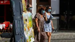 Turis berjalan-jalan di distrik Montmartre, Paris pada Senin (10/8/2020). Pemerintah Kota Paris mengumumkan masker wajib dipakai di area luar ruangan yang ramai di ibu kota Prancis itu mulai Senin (10/8) untuk mengendalikan peningkatan tingkat infeksi virus corona. (AP Photo/Michel Euler)