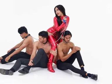 Penyanyi Denada mengenakan baju merah ketat dan sepatu boot berwarna senada. bersama tiga laki-laki yang sedang duduk dalam kondisi topless denada bergoyang di single terbarunya bertajuk "Mutha Futha". (Instagram/@denadaindonesia)