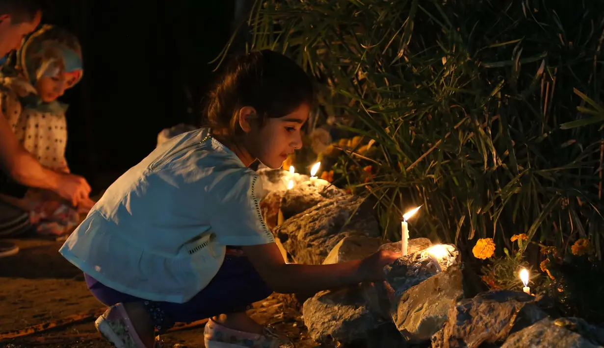 Seorang anak menyalakan lilin di luar kuil Imam al-Mahdi selama upacara Shaabaniya memperingati kelahiran Imam, tokoh paling suci untuk umat Syiah, di kota Karbala, Irak tengah, (2/5). (AFP Photo/Mohammad Sawaf)