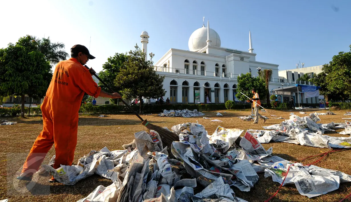 Beberapa petugas kebersihan membersihkan lapangan Lapangan Masjid Agung Al Azhar, Jakarta usai pelaksanaan salat Idul Fitri 1436 H, Jumat (17/7/2015). Sisa koran bekas dikumpulkan dan dimanfaatkan oleh pemulung. (Liputan6.com/Yoppy Renato)