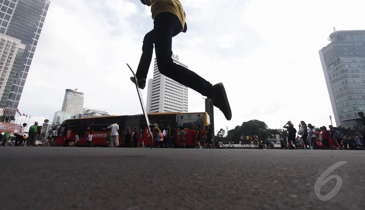Seorang remaja mencoba trik lompat dengan skateboard di kawasan Bundaran HI Jakarta, Minggu (14/12/2015). (Liputan6.com/Faizal Fanani)