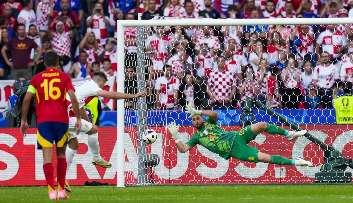 Kiper Timnas Spanyol, Unai Simon berhasil mementahkan eksekusi penalti striker Timnas Kroasia, Bruno Petkovic pada laga Grup B Euro 2024 di Olympiastadion, Berlin, Jeman, Sabtu (15/6/2024). (AP Photo/Manu Fernandez)