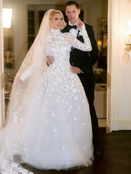 Saat menikah Paris tampil elegan dengan gaun pernikahan putihnya membuatnya seperti princess. Sedangkan sang saumi dengan setelan jas hitam lengkap dengan dasi kupu-kupu. (@parishilton)