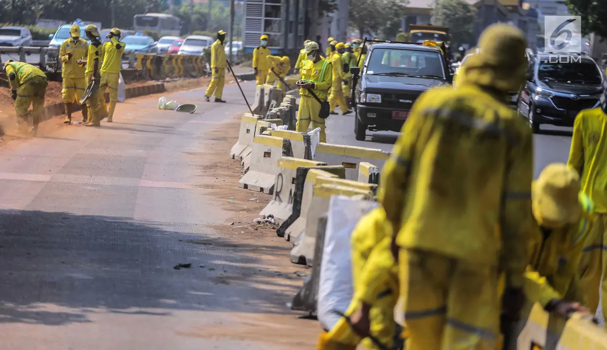 Petugas Dinas Bina Marga DKI Jakarta memperbaiki separator busway di kawasan Jalan Gatot Subroto, Jakarta, Selasa (1/10/2019). Separator busway dirusak massa saat terjadi bentrok antara polisi dengan demonstran di kawasan tersebut. (Liputan6.com/Faizal Fanani)