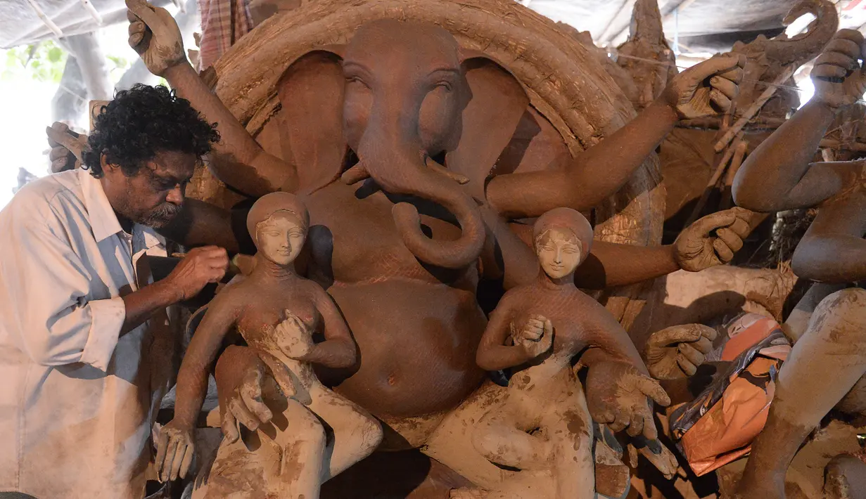 Seorang seniman India menyelesaikan pembuatan patung Dewa Hindu, Lord Ganesh di sebuah lokakarya di Hyderabad (19/8/2019). Patung ini dibuat dengan bahan-bahan ekologis untuk mengurangi polusi selama perendaman untuk festival Ganesh Chaturthi. (AFP Photo/Noah Seelam)