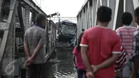Warga mengamati evakuasi bus TransJakarta yang terperosok ke sungai usai ditabrak kereta api Senja Utama Solo di perlintasan kereta Mangga Dua, Jakarta, Kamis (19/5). Sopir mobil Avanza dan TransJakarta mengalami luka-luka. (Liputan6.com/Faizal Fanani)