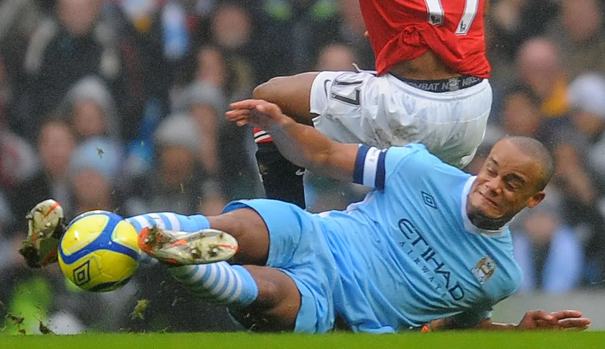 Pemain Manchester City, Vincent Kompany melakukan tekel kepada pemain Manchester United, Nani pada laga putaran ketiga Piala FA 2011/2012 yang berlangsung di Etihad Stadium, Manchester, 8 Januari 2012. (AFP/Andrew Yates)