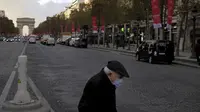 Seorang pria lanjut usia mengenakan masker saat melintas di jalan Champs Elysee, Paris, Kamis (19/11/2020). Prancis telah melampaui 2 juta kasus virus corona COVID-19 yang dikonfirmasi, total tertinggi keempat di dunia. (AP Photo/Thibault Camus)
