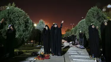 Umat Syiah Iran menempatkan salinan Al Quran diatas kepala mereka saat berdoa pada malam Ramadan di Teheran, Iran (16/6). Mereka berdoa mengharapkan mendapat malam Lailatul Qadar. (AP Photo/Vahid Salemi)