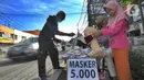 Seorang ibu ditemani anaknya melayani pembeli saat berjualan masker kain buatan rumahan di Jalan Raya Cinere-Depok, Limo, Depok, Rabu (8/4/2020).  Anjuran pemerintah mengenai penggunaan masker kain dimanfaatkan ibu ini untuk berjualan masker kain. (merdeka.com/Arie Basuki)