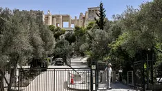 Seorang karyawan menutup gerbang akses ke situs arkeologi Acropolis di Athena pada 14 Juli 2023. (AFP/Spyros Bakalis)