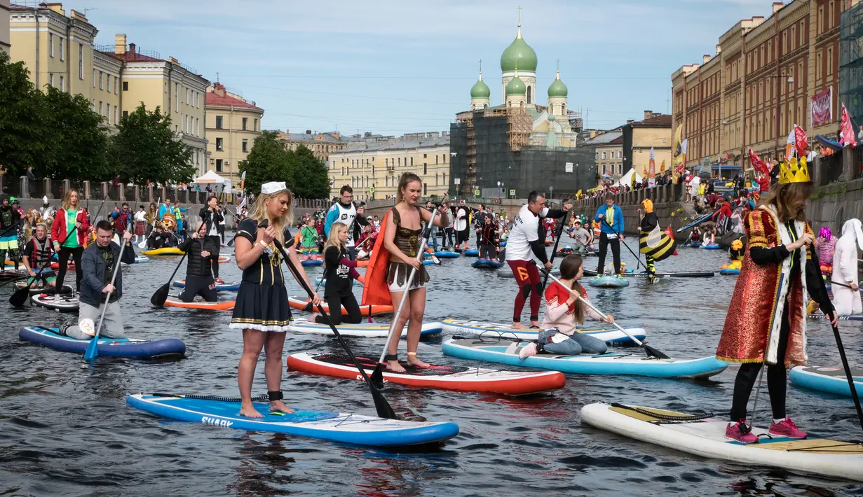 Sejumlah peserta mengenakan kostum mendayung papan Stand Up Paddle (SUP) di kanal Kryukov saat Surfing festival di St.Petersburg, Rusia (8/7). Olahraga ini tidak hanya dimainkan di laut saja, tetapi bisa disungai atau danau. (AP Photo / Dmitri Lovetsky)