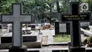 Keluarga membersihkan makam saat ziarah di kompleks pemakaman Gereja Tugu, Semper, Jakarta, Senin (23/12/2019). Ziarah menjadi tradisi keluarga keturunan Portugis di Kampung Tugu menjelang Hari Raya Natal. (merdeka.com/Iqbal Nugroho)