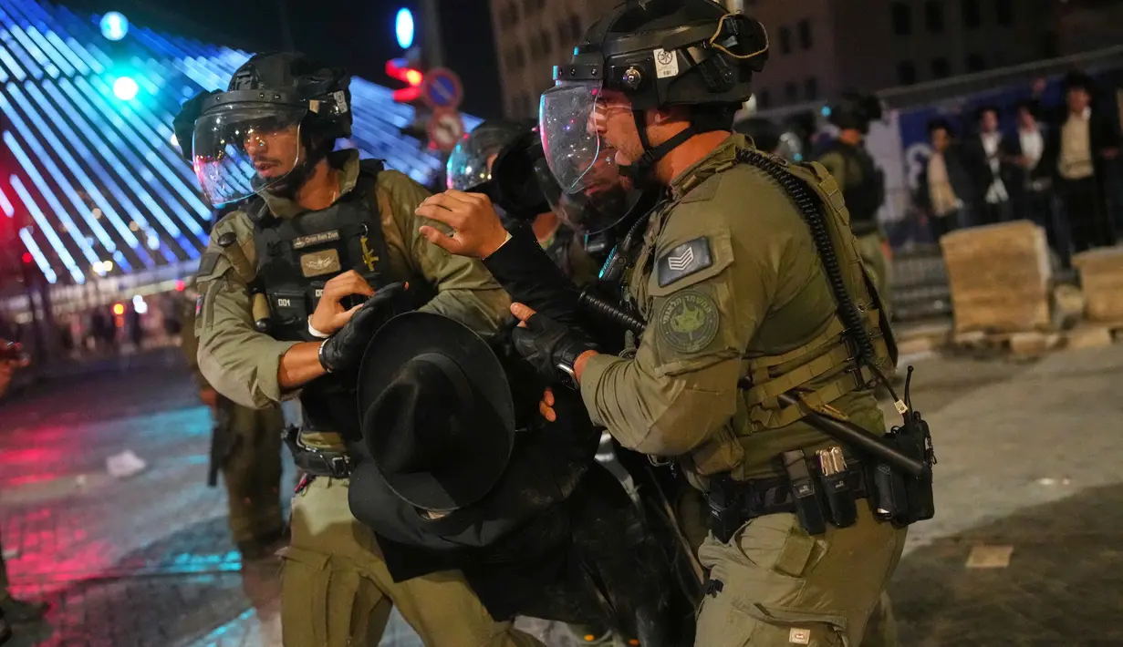 Petugas polisi Israel membubarkan pria Yahudi ultra-Ortodoks yang menghalangi jalan dalam aksi protes menentang rencana wajib militer mereka di militer Israel, di Yerusalem, Kamis 30 Oktober 2025. Setelah beberapa jam, polisi menggunakan meriam air untuk membubarkan para demonstran. (AP Photo/Ohad Zwigenberg)