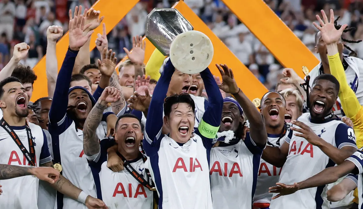 Son Heung-min (tengah) mengangkat trofi bersama para pemain Tottenham setelah menjuarai final Liga Europa 2024/2025 di Stadion San Mames, Bilbao, Spanyol, Kamis (22/05/2025) WIB. Tottenham menang dengan skor 1-0 atas Manchester United. (AFP/Thomas Coex)