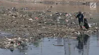 Pemulung mencari barang bekas di tumpukan sampah yang muncul di permukaan Kanal Banjir Barat, Jakarta, Selasa (16/7/2019). Kemarau sejak dua bulan ini menyebabkan sampah-sampah yang mengendap di dasar sungai muncul ke permukaan sehingga menimbulkan bau tak sedap. (merdeka.com/Iqbal S Nugroho)