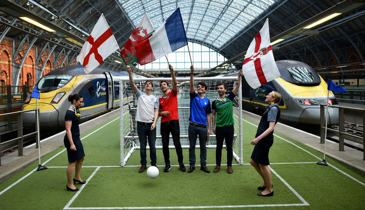 Beberapa warga mengibarkan bendera Inggris, Wales, Prancis, dan Irlandia Utara di sebuah lapangan sepak bola mini dalam Stasiun St. Pancras, London, (8/6/2016), untuk menyambut Piala Eropa 2016. (AFP/Ben Stansall)