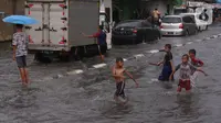 Sejumlah anak bermain banjir saat melanda jalan Bayangkara Pusdiklat, Kota Tangerang Selatan, Banten, Selasa (2/11/2021). Aksi anak anak tersebut dapat membahayakan keselamatan jiwa karena banyaknya kendaraan yang melintas menerjang banjir. (Liputan6.com/Angga Yuniar)