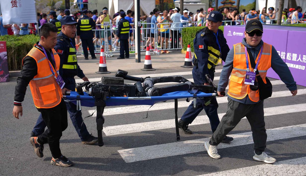 Meski beberapa robot sempat mengalami kendala teknis, mulai dari kesulitan memulai lomba hingga gagal mencapai garis finis. Tampak dalam foto, petugas keamanan dan peserta menggunakan tandu untuk membawa robot setelah robot tersebut berkompetisi dalam Beijing E-Town Half Marathon dan Humanoid Robot Half-Marathon di pinggiran Beijing, Minggu 19 April 2026. (AP Photo/Andy Wong)