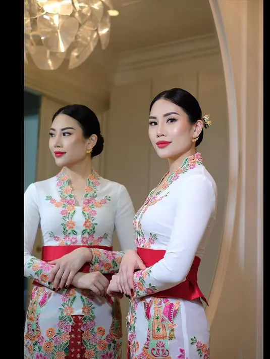 Berwajah oriental, Angela Tanoesoedibjo tampil begitu menawan mengenakan kebaya model encim warna putih dengan aksen bordiran bunga warna-warni. [Instagram/loritayoung_mua]