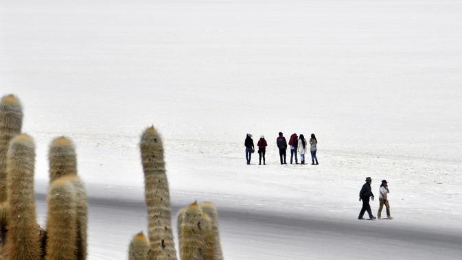 Wisatawan mengunjungi Salar de Uyuni, dataran garam terluas di dunia yang terletak di Altiplano, barat daya Bolivia pada 28 September 2019. Setiap tahunnya sekitar 25.000 ton garam dihasilkan dari dataran ini. (Photo by Aizar RALDES / AFP)