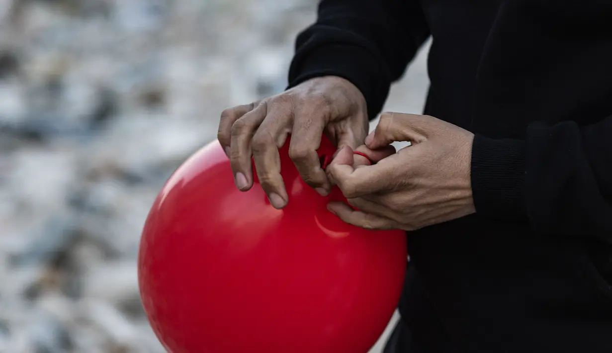 Ogun Sever Okur, pria Turki berusia 38 tahun mengikat balon untuk menggantungnya di puing-puing bangunan yang runtuh di Antakya, Turki selatan pada 21 Februari 2023, menyusul gempa berkekuatan 6,4 yang melanda pada 20 Februari, dua minggu setelahnya. gempa berkekuatan 7,8 melanda dekat Gaziantep dan telah menewaskan lebih dari 44.000 orang. (AFP/Sameer Al-Doumy)
