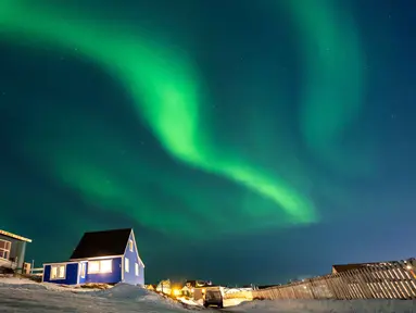 Aurora Borealis menerangi langit malam di atas rumah-rumah penduduk di Nuuk, Greenland, pada 23 Januari 2026. Cahaya hijau bersinar menghiasi langit kota Nuuk, Greenland, pada Jumat 23 Januari 2026 waktu setempat. (Jonathan NACKSTRAND/AFP)