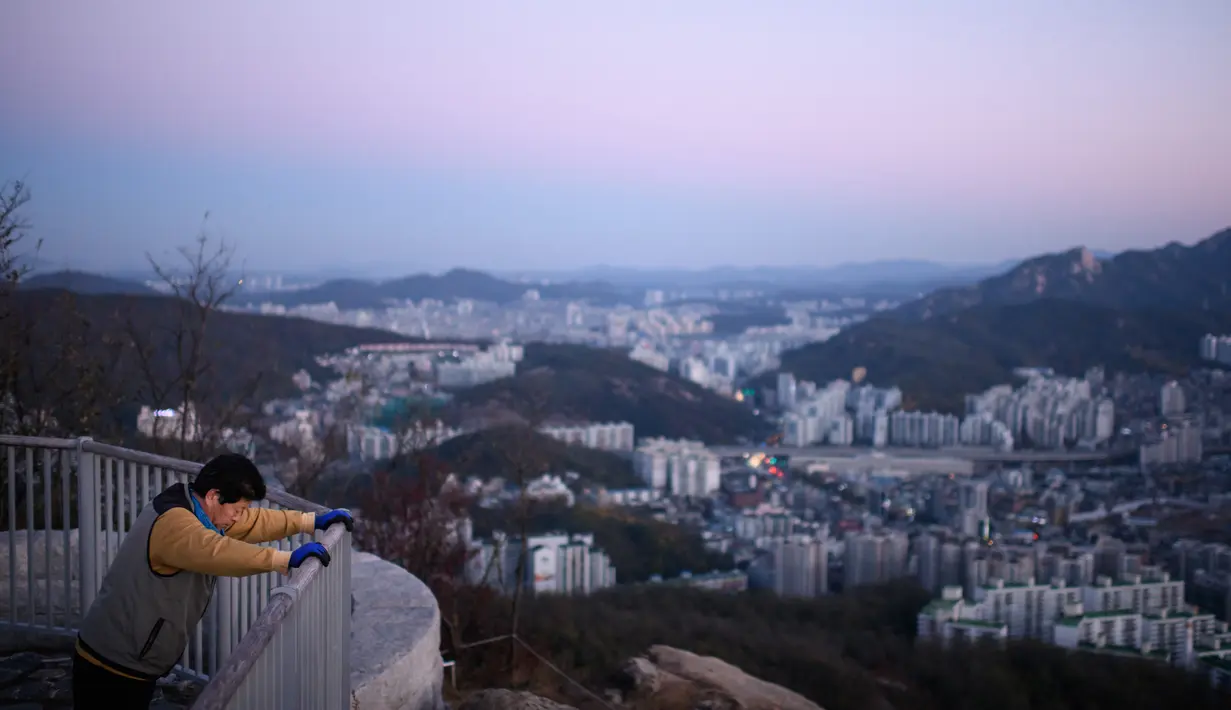 Pejalan kaki berolahraga dengan dengan pemandangan kota Seoul selama matahari terbit di Korsel (31/10). Seoul merupakan salah satu kota terpadat di dunia. Kepadatannya telah membuatnya menjadi salah satu kota digital-kabel di dunia. (AFP Photo/Ed Jones)