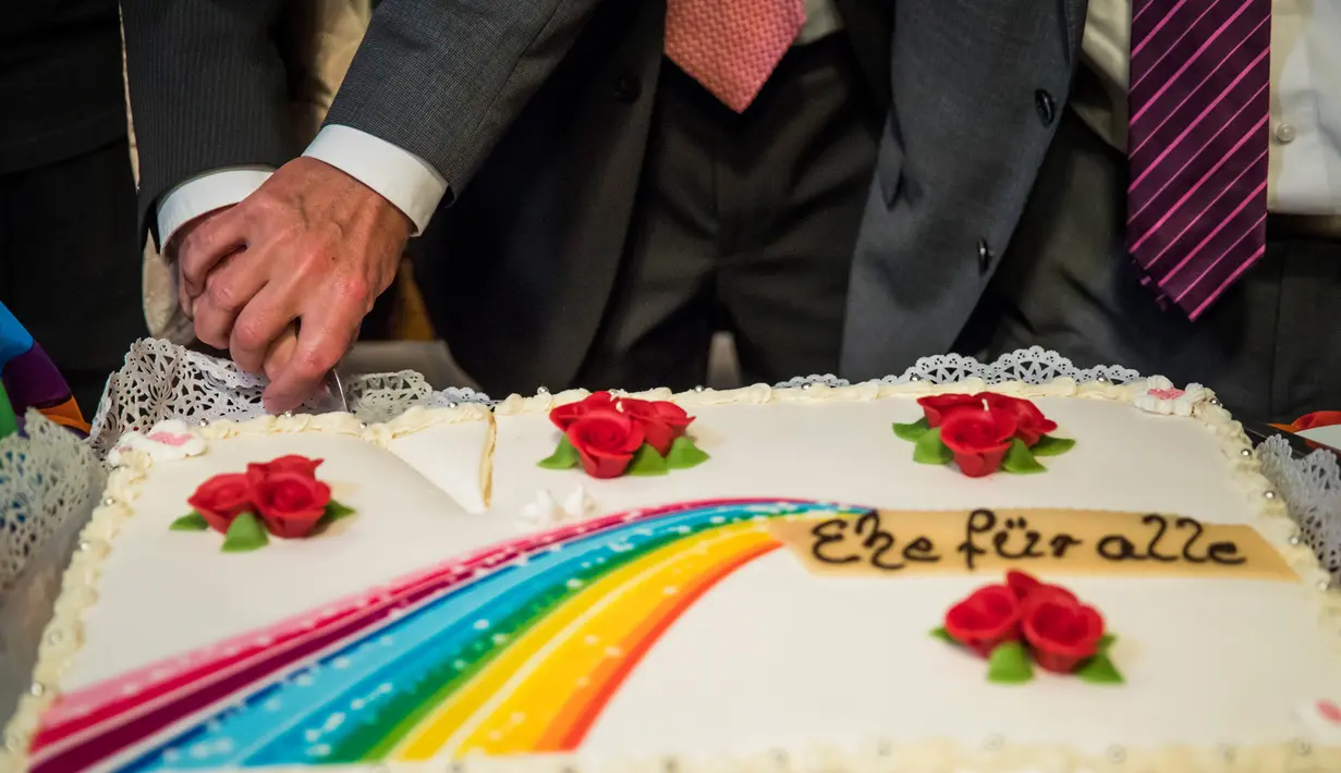 Pasangan gay, Bode Mende dan Karl Kreile memotong kue saat prosesi pernikahannya di balai kota Schoeneberg di Berlin, Jerman (1/10). Jerman termasuk 20 negara yang melegalkan pernikahan sesama jenis. (AFP Photo/Odd Andersen)
