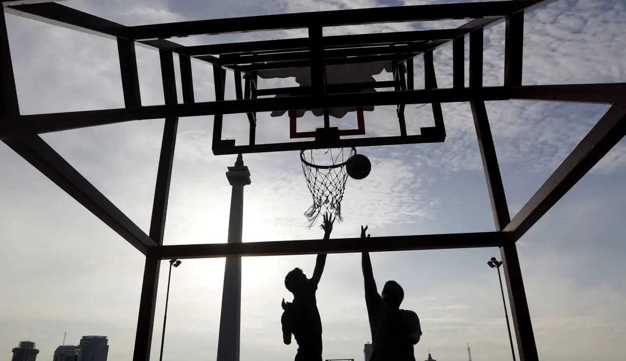 Dua orang warga berusaha memasukan bola saat olahraga basket di Kawasan Monumen Nasional, Jakarta, Rabu (13/2). Monas merupakan salah satu lokasi yang kerap dijadikan ruang olahraga bagi warga ibukota. (Bola.com/M. Iqbal Ichsan)