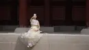Seorang wanita mengenakan pakaian tradisional Korea, Hanbok sambil berswafoto di istana Gyeongbokgung, Seoul, Rabu (26/9). Korea Selatan sedang menikmati hari terakhir dari liburan Chuseok atau Hari Thanksgiving. (AFP PHOTO / Ed JONES)
