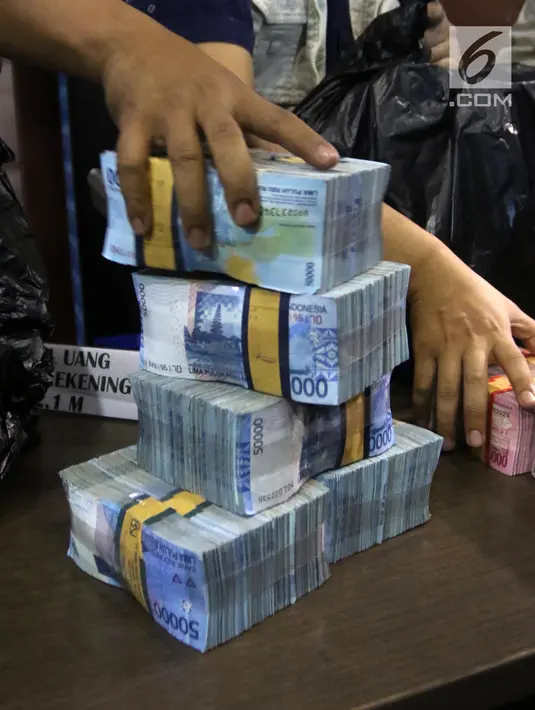 Petugas BNN menunjukkan barang bukti uang hasil tindak pidana pencucian uang (TPPU) di Jakarta, Selasa (17/7). TPPU ini terbongkar dari pengembangan kasus napi bernama Irawan alias Dagot di Rutan kelas 11A Pontianak. (Liputan6.com/Arya Manggala)
