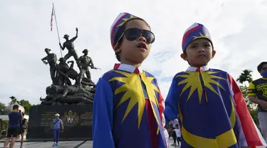 Dua anak laki-laki yang mengenakan kostum bendera nasional Malaysia berfoto di depan Monumen Nasional saat perayaan Hari Nasional ke-64 untuk memperingati kemerdekaan dari penjajahan Inggris di Kuala Lumpur, Malaysia, Selasa (31/8/2021). (AP Photo/Vincent Thian)
