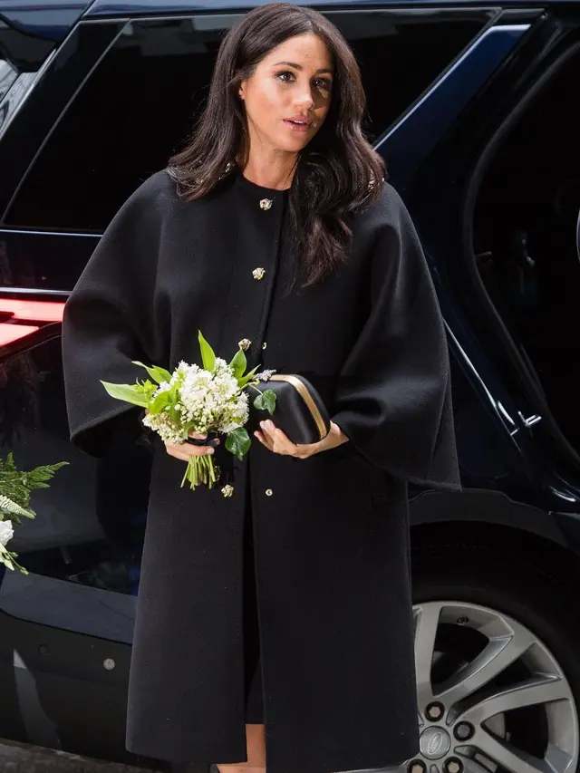 Meghan Markle mengenakan tas Black Satin Clutch.
