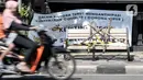 Pengendara melintasi bangku trotoar yang disegel garis pembatas dan ditutupi bambu di kawasan Rawamangun, Jakarta, Minggu (3/5/2020). Bangku trotoar di sepanjang jalan Rawamangun disegel untuk mencegah kerumunan warga sebagai upaya memutus rantai penyebaran COVID-19. (merdeka.com/Iqbal S. Nugroho)