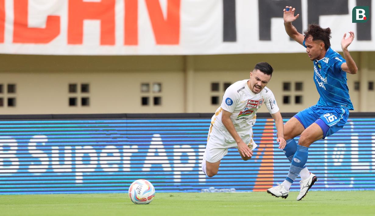 Pemain Persija Jakarta, Oliver Bias, terjatuh berusaha melewati pemain Persib Bandung, Rezaldi Hehanusa, pada laga pekan ke-28 Liga 1 2023/2024 di Stadion Si Jalak Harupat, Bandung, Sabtu (9/3/2024). (Bola.com/M Iqbal Ichsan)