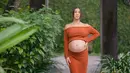 Ia mengenakan long sleeve sabrina dan rok berwarna terracotta sembari pamer baby bump [instagram/namasaweddings]