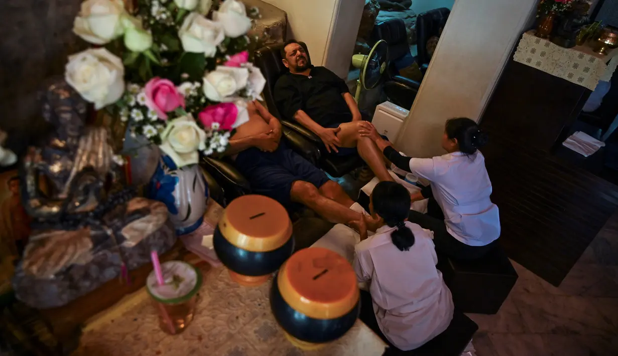 Gambar pada 3 Desember 2019, wisatawan melakukan pijat di pusat pijat tradisional Thailand di kompleks Wat Pho, Bangkok. Dari spa mewah di Bangkok, tepi Pantai Phuket hingga berbagai panti pijat sederhana di daerah perkotaan, Nuad Thai atau pijat ala Thailand mudah sekali ditemukan (Romeo GACAD/AFP)