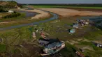 Perahu dan rumah-rumah terlihat terdampar di Danau Aleixo akibat kekeringan parah di sebelah barat Manaus, Negara Bagian Amazonas, Brasil, pada 20 September 2024. (MICHAEL DANTAS/AFP)