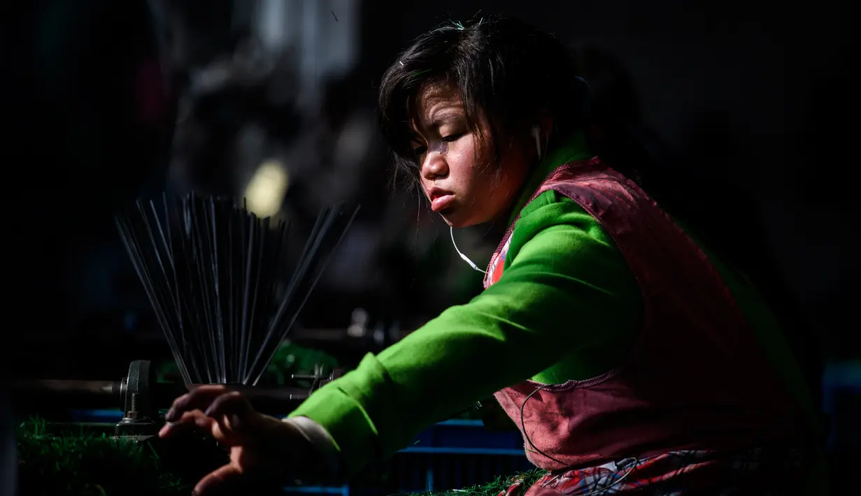 Pekerja menyelesaikan pembuatan pohon Natal di pabrik Sun Xudan, Yiwu, China (7/12). Sun Xudan adalah pabrik terbesar di China yang memproduksi berbagai aksesoris Natal, termasuk pohon cemara buatan. (AFP Photo/Johannes Eisele)