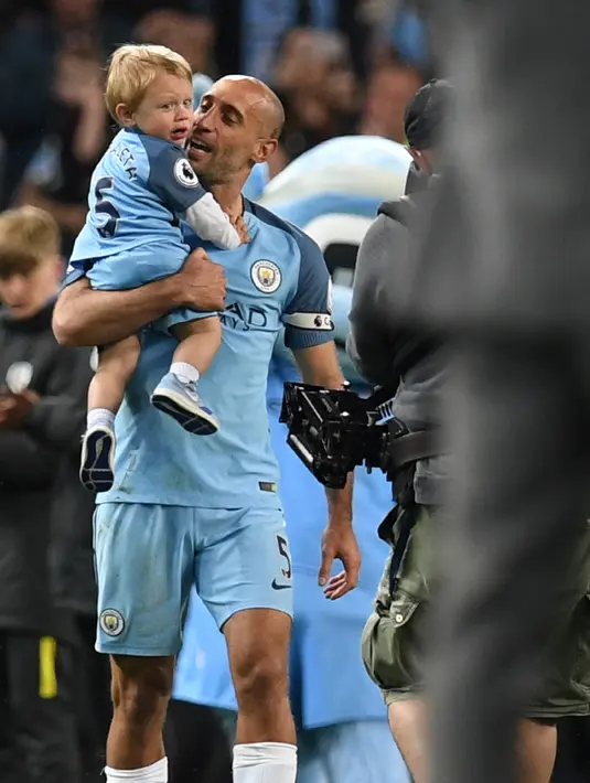 Pablo Zabaleta menggendong putranya Asier usai pertandingan melawan West Bromwich Albion di Liga Inggris di Stadion Etihad, Manchester,(16/5). Zabaleta kabarnya akan berlabuh ke West Ham dengan kontrak dua tahun. (AFP Photo/Paul Ellis)