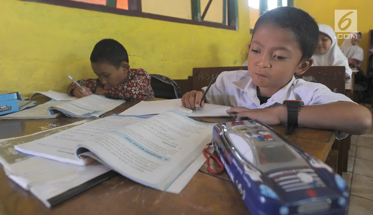 Mukhlis Abdul Holik (8) mengikuti kegiatan belajar di SDN 10 Cibadak Sekarwangi, Sukabumi, Kamis (15/11). Keterbatasan fisik sejak lahir tidak menyurutkan semangat Adul untuk meraih ilmu demi menggapai cita-citanya. (Merdeka.com/Arie Basuki)