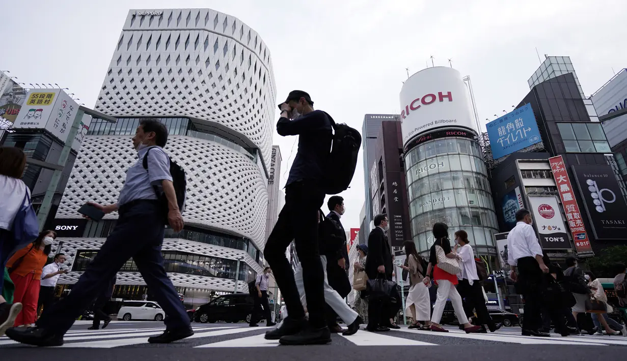 Orang-orang mengenakan masker mencegah penyebaran coronavirus baru berjalan di atas penyeberangan pejalan kaki di Tokyo, Senin, (20/7/2020). Ibukota Jepang hari Senin mengkonfirmasi lebih dari 160 kasus virus corona baru. (AP Photo/Eugene Hoshiko)