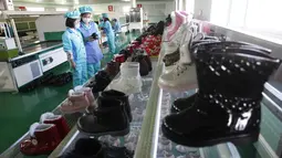 Sepatu-sepatu dipajang saat para pekerja yang memakai masker bekerja di Pabrik Sepatu Kulit Wonsan, tempat mereka memproduksi sepatu kulit buatan tangan di Wonsan, Provinsi Kangwon, Korea Utara pada 28 Oktober 2020. (AP Photo/Jon Chol Jin)