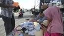 Seorang ibu ditemani anaknya melayani pembeli saat berjualan masker kain buatan rumahan di Jalan Raya Cinere-Depok, Limo, Depok, Rabu (8/4/2020).  Sebelumnya ia berjualan di pasar malam, namun semenjak larangan berjualan di pasar malam ia berjualan di pinggi jalan.  (merdeka.com/Arie Basuki)