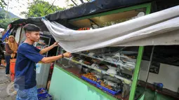 Seorang penjual menutup warung makannya dengan kain, Jakarta, Selasa (7/6/2016). Selama bulan puasa, sejumlah warung makan di kawasan perkantoran memilih untuk tutup di siang hari. (Liputan6.com/Yoppy Renato)