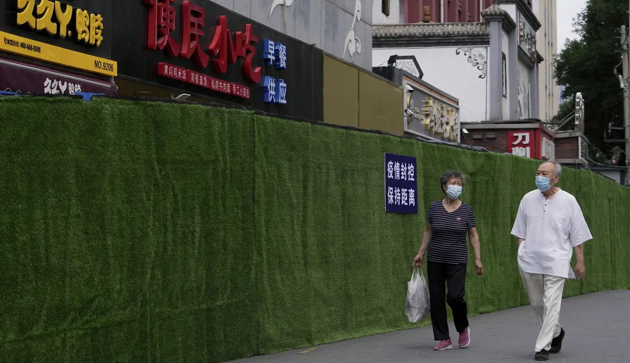 <p>Warga dengan masker berjalan di sepanjang penghalang di sekitar toko ritel dan restoran yang telah dikunci sebagai bagian dari pengendalian COVID-19 di Beijing, Selasa (14/6/2022). Pihak berwenang memerintahkan pengujian massal tiga hari untuk penduduknya di distrik Chaoyang menyusul terdeteksinya ratusan kasus virus corona COVID-19 terkait dengan klaster bar 24 jam. (AP Photo/Andy Wong)</p>